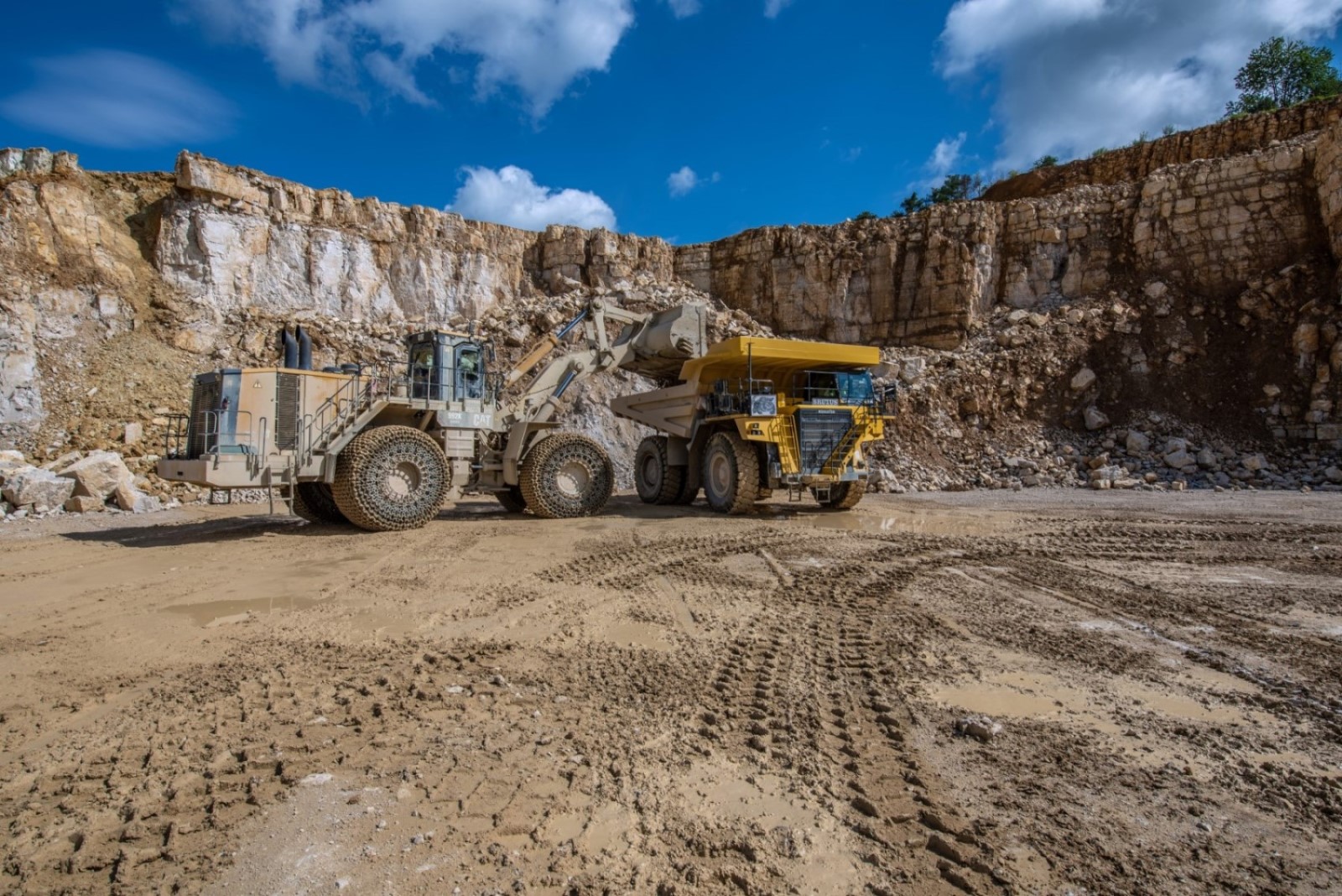 Transport des Rohmaterials - Ein Radlader belädt einen Muldenkippper. Dieser tansportiert das Rohmaterial zu der Brecheranlage im Steinbruch.