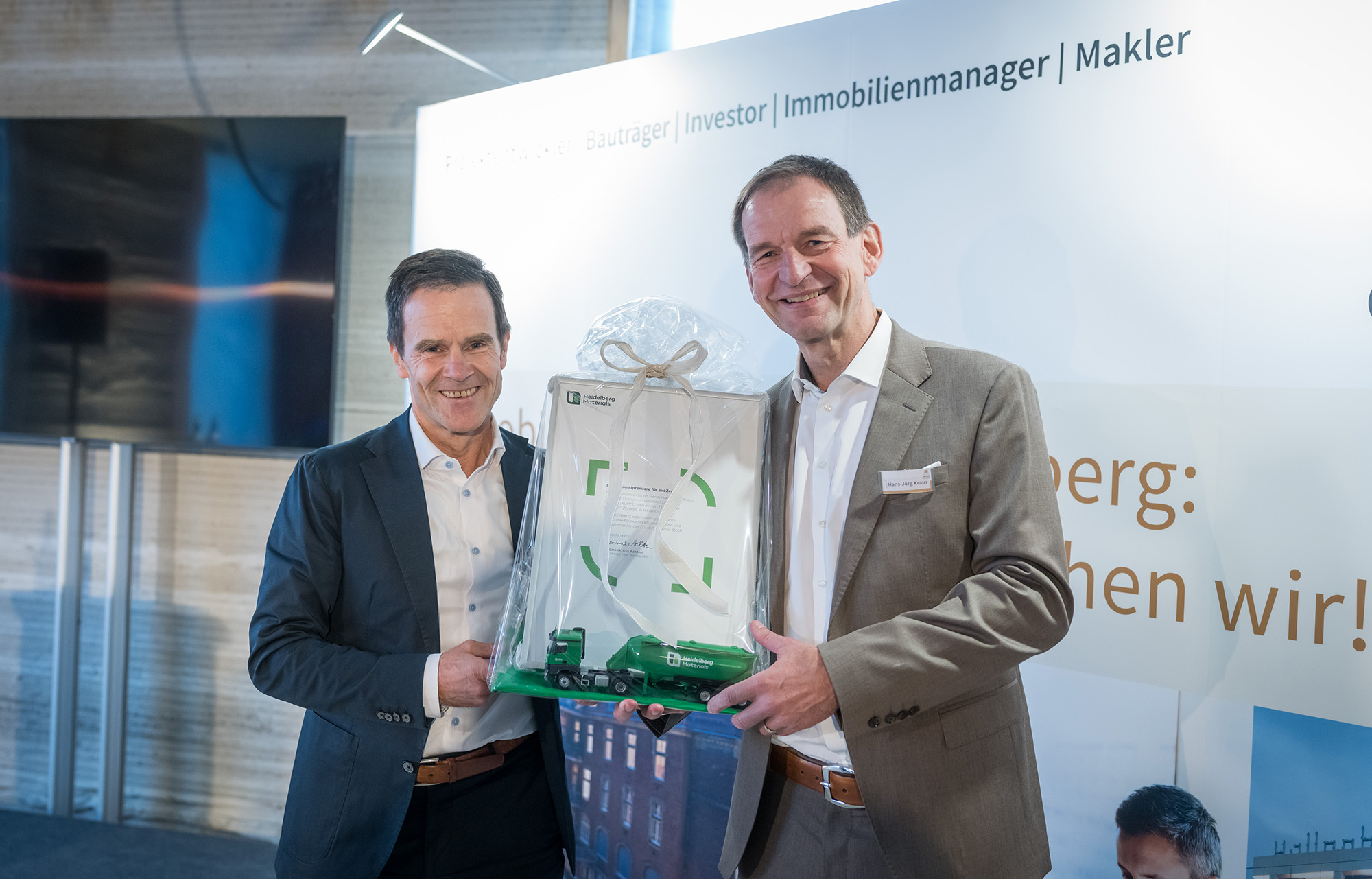 Bestätigung für den ersten Einsatz eines Carbon-Captured Zements in Deutschland: Dr. Dominik von Achten, Vorstandsvorsitzender Heidelberg Materials AG (l.) und Hans-Jörg Kraus, geschäftsführender Gesellschafter der KRAUSGRUPPE (r.) und Bauherr des DREIHAUS-Referenzobjektes.