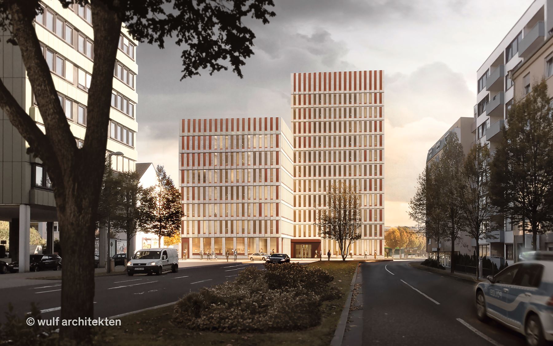 Zwei moderne, rechteckige Bürogebäude mit einer Fassade aus vertikal gegliederten Elementen stehen nebeneinander in einer städtischen Straße. Links und rechts der Straße befinden sich weitere Gebäude und parkende Fahrzeuge. Im Vordergrund liegt eine bepflanzte Verkehrsinsel, im Hintergrund ist ein heller Himmel mit warmem Abendlicht zu sehen.   Die Visualisierung zeigt die beide Baukörper des neues Polizeipräsidiums Rheinpfalz in Ludwigshafen. Die Ansicht entlang der Straße verdeutlicht die Höhenstaffelung 