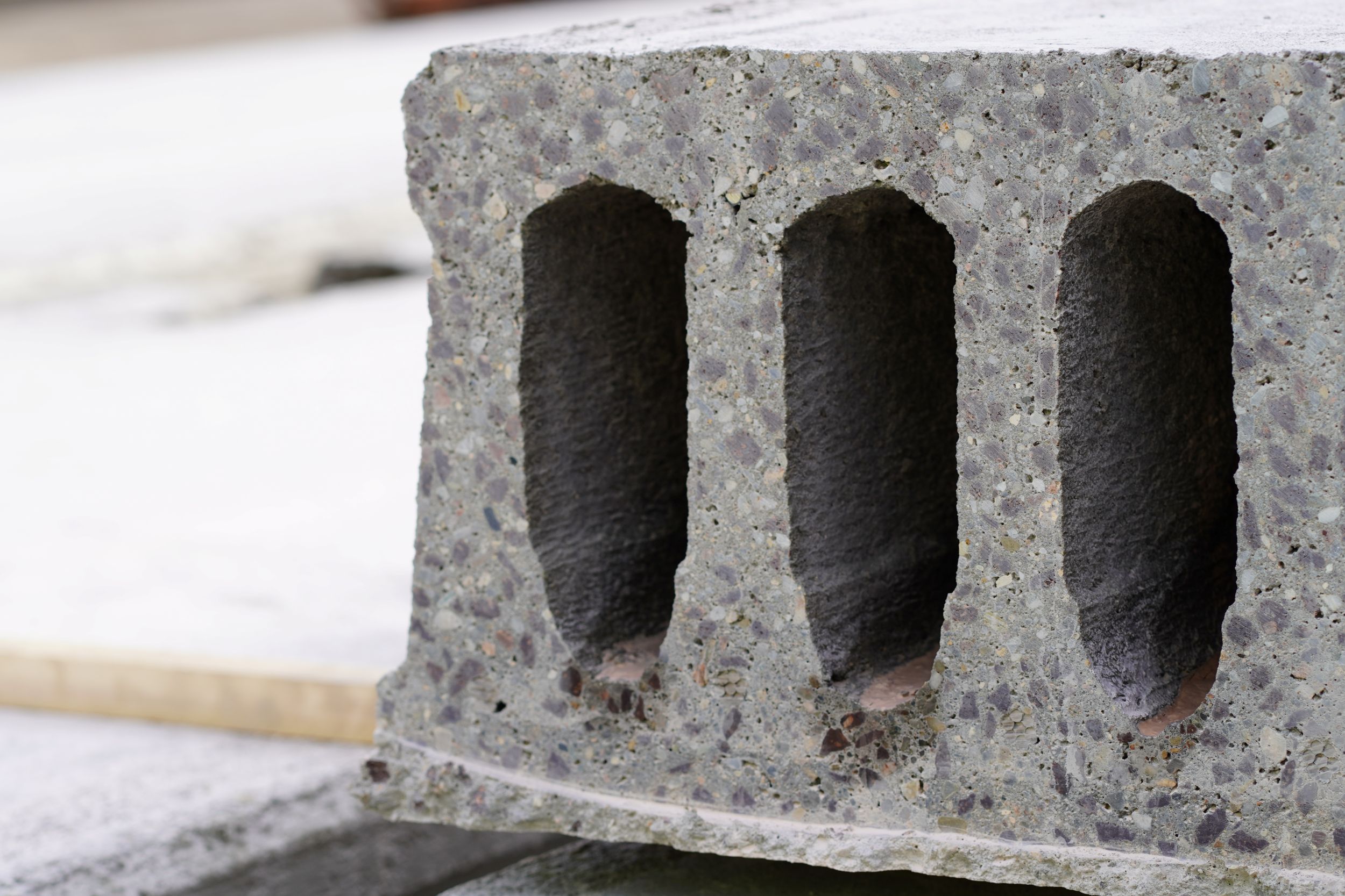 Betonblock mit drei Hohlräumen liegt auf einer Baustelle.