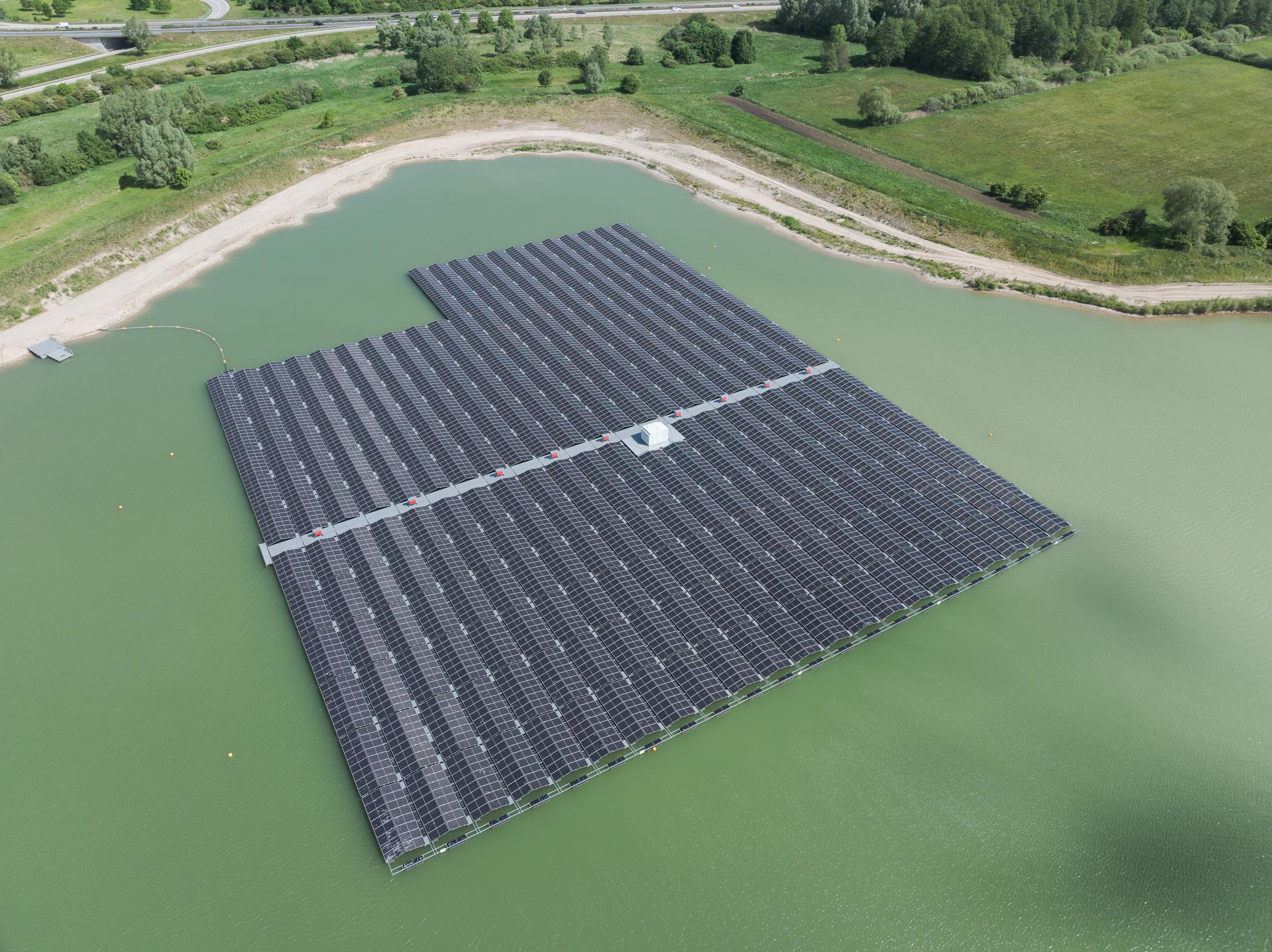 Eine schwimmende Solaranlage auf einem Gewässer in einer grünen Landschaft.