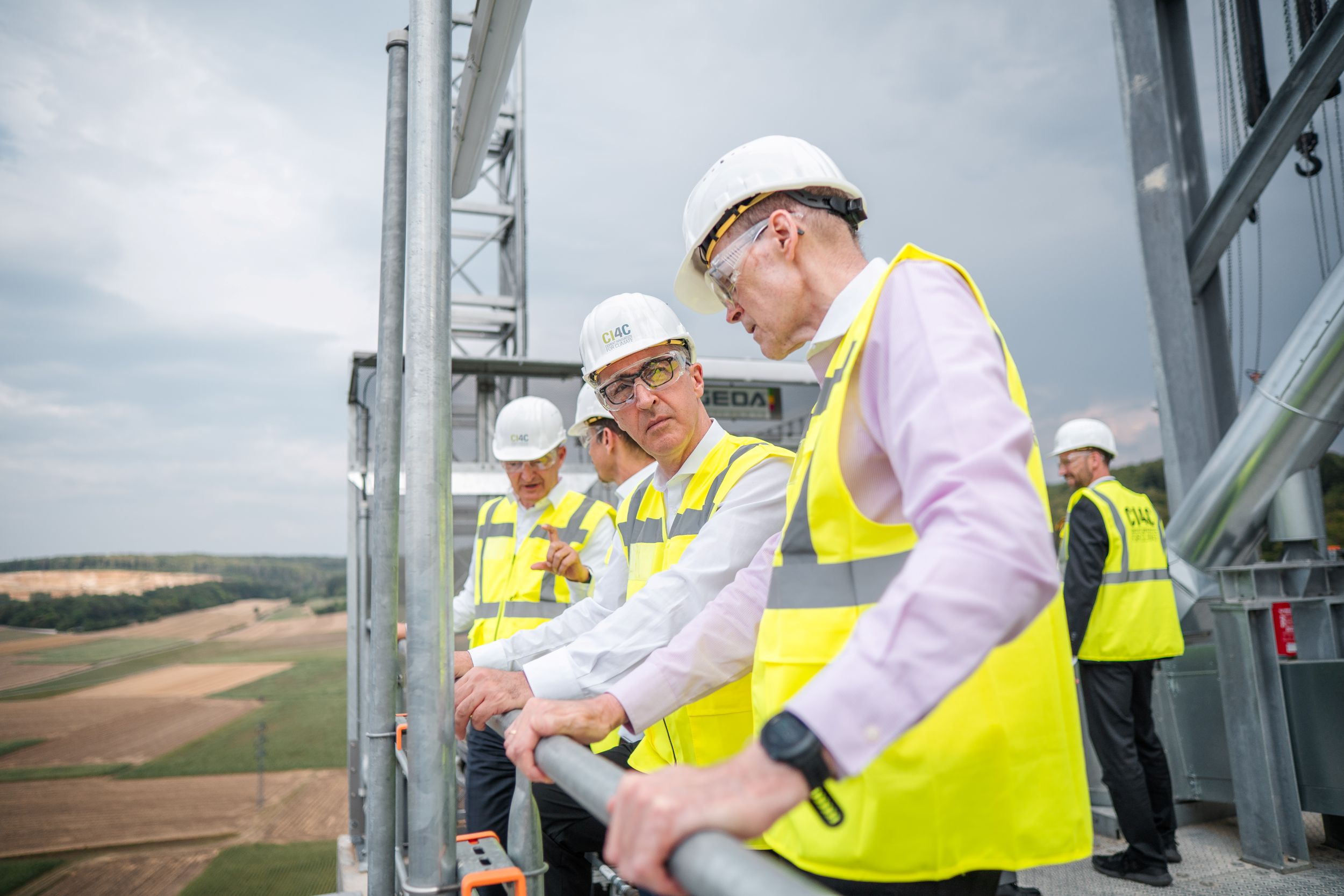 Mitarbeiter in Bauhelmen und Sicherheitswesten auf einer Baustelle.