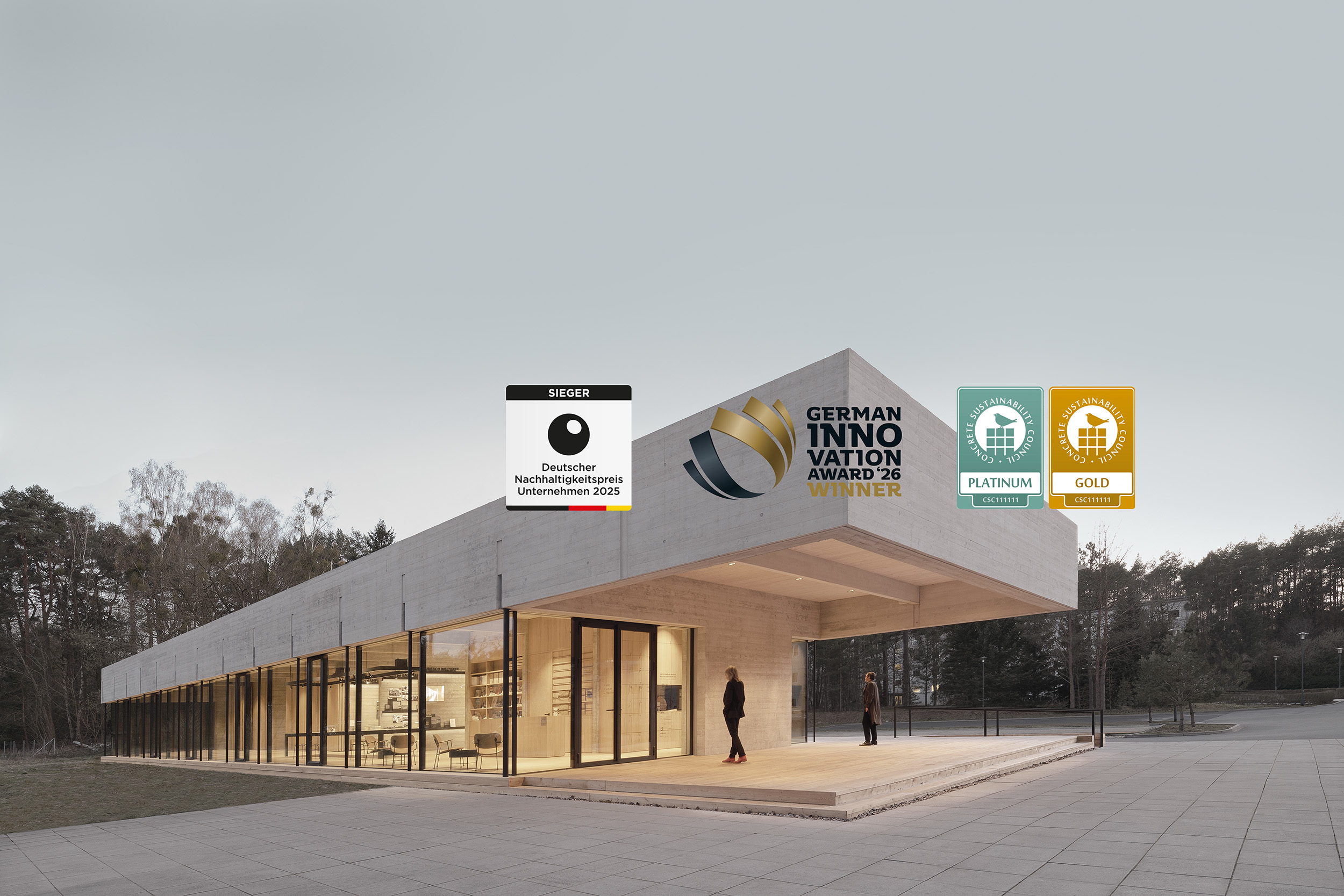 Modernes Gebäude mit großen Glasfassaden, umgeben von einer natürlichen Landschaft. Darauf Siegel für Deutschen Nachhaltigkeitspreis, German Innovation Award und CSC-Zertifikate.