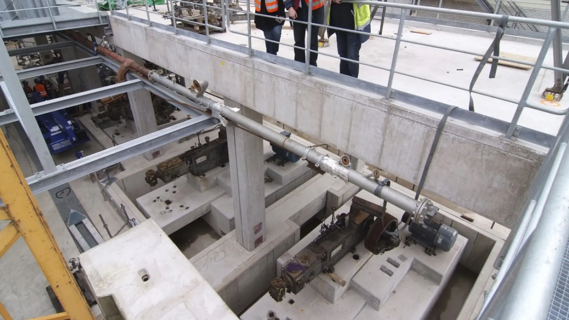 Mitarbeiter in Schutzkleidung begutachten eine Industrieanlage auf einer Baustelle.