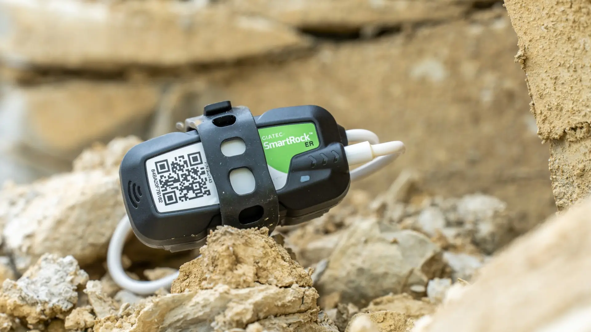 Elektronisches Sensorgerät liegt auf sandigem Bauschutt in einer Baustellenumgebung.