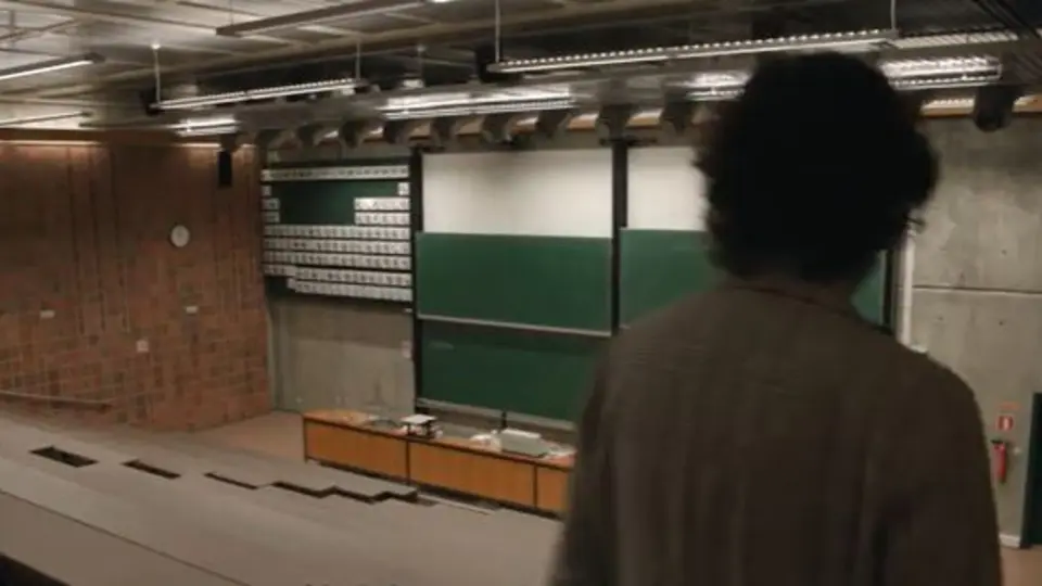 Blick in einen Hörsaal, eine Person ist von hinten zu sehen