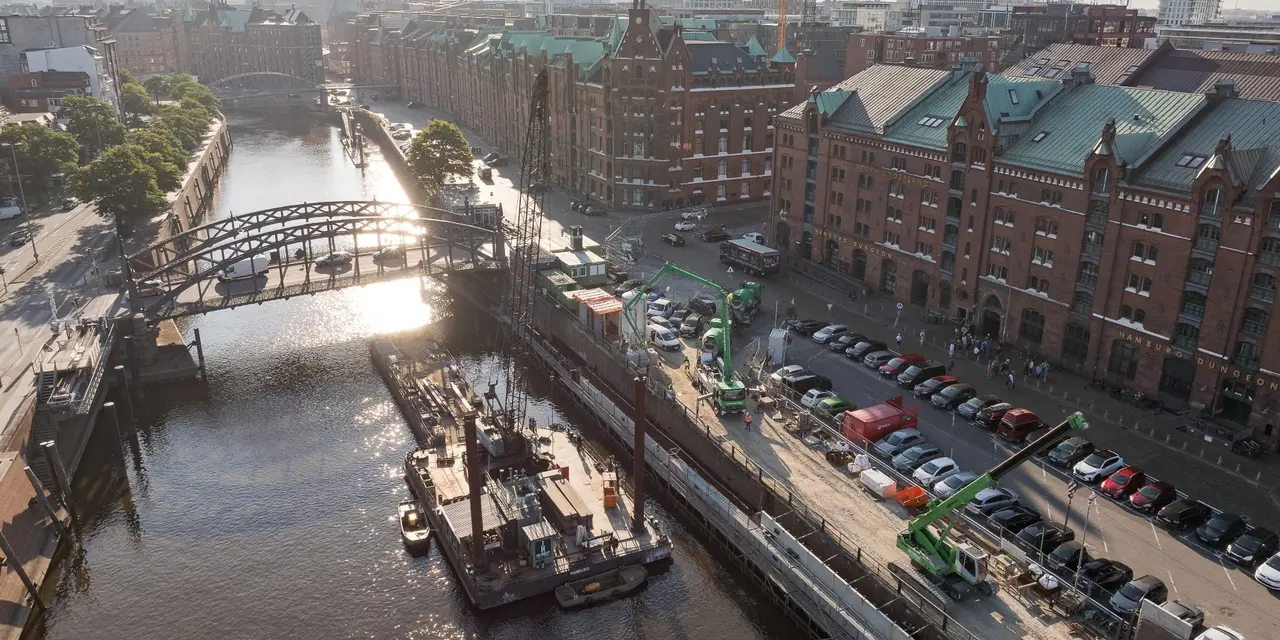Luftaufnahme einer Baustelle in der Hamburger Speicherstadt mit umliegenden historischen Gebäuden und Kränen.