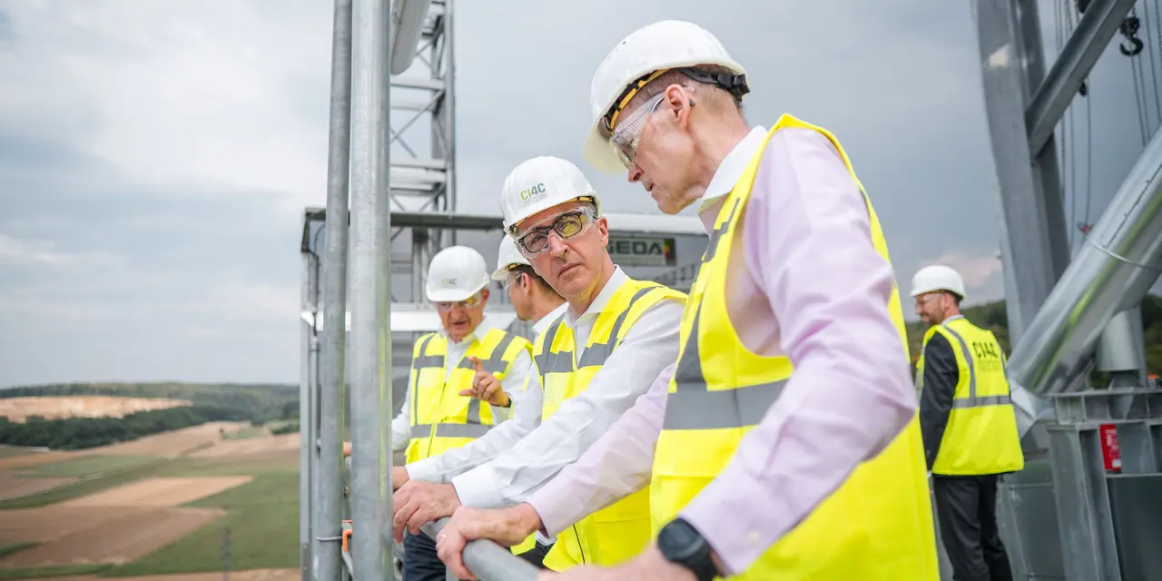 Mitarbeiter in Bauhelmen und Sicherheitswesten auf einer Baustelle.
