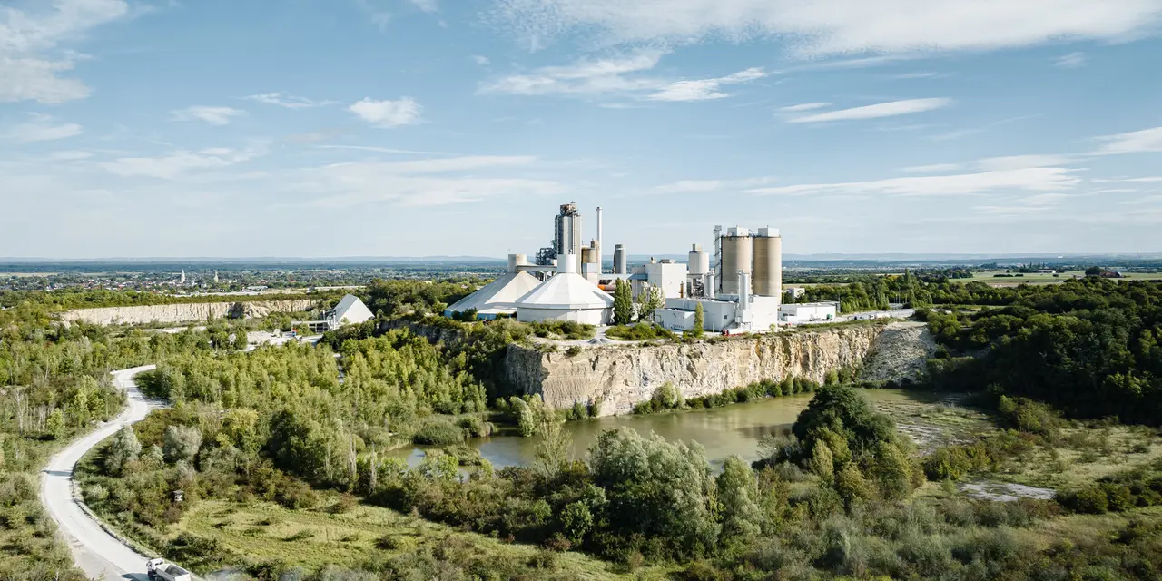 Zementwerk von Heidelberg Materials mit umliegender grüner Landschaft.