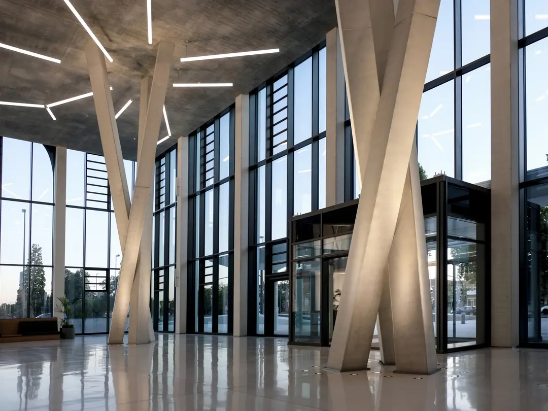 Modernes Gebäudefoyer mit großen Glasfronten und schlanken Betonstützen.