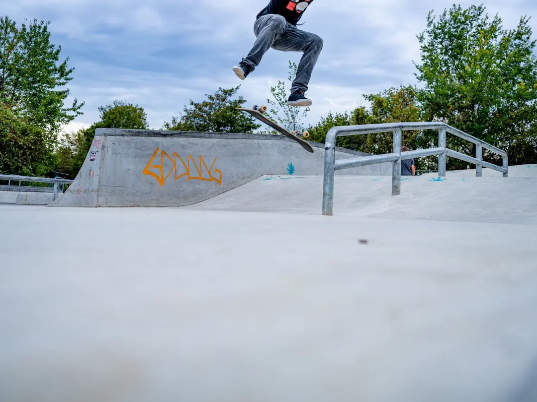 Ein Skateboarder führt einen Trick in einem Beton-Skatepark aus.