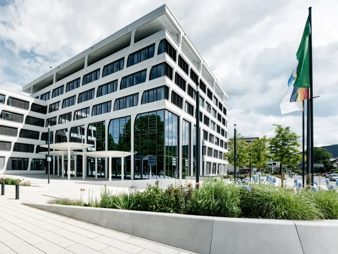 Hauptverwaltung von Heidelberg Materials mit klarer Glas- und Fassadenstruktur, umgeben von einer begrünten Außenanlage.