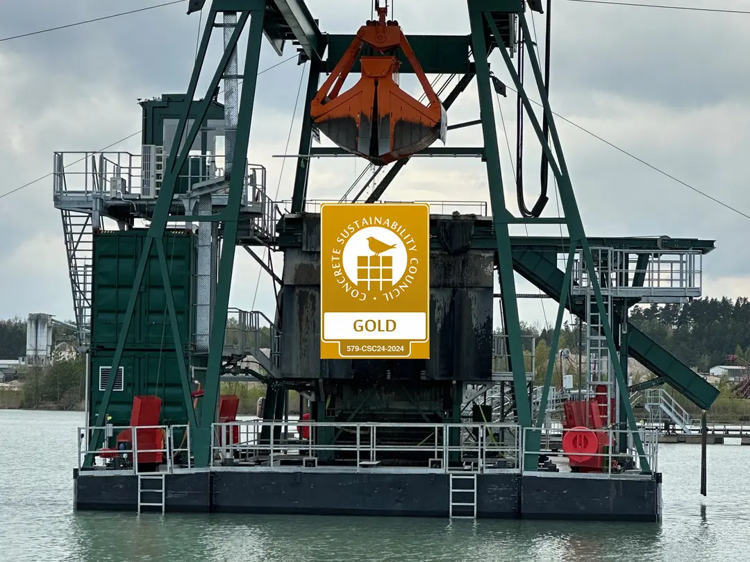 Bagger auf einem Gewässer, mit einem Heidelberg Materials-Logo in der Mitte.