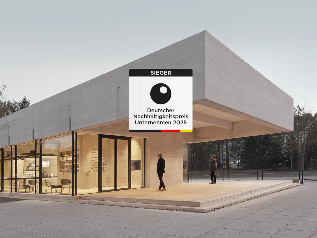 Ein modernes Gebäude aus Beton mit großen Glasflächen, umgeben von einer offenen Außenfläche.