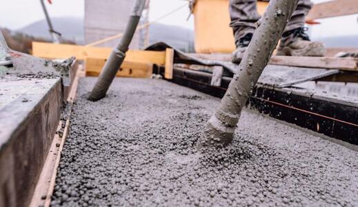 Beton wird auf einer Baustelle gegossen, mit Vibriergeräten verdichtet.