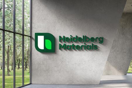 Heidelberg Materials Logo auf einer Betonwand in einer modernen, lichtdurchfluteten Umgebung.