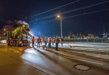 Arbeiter in orange Westen betonieren nachts eine Baustelle mit ChronoCrete.