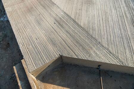 Nahaufnahme vom Recyclingbeton als Fahrbahndecke. Betonplatte mit einer strukturierten Oberfläche, die diagonale Rillen aufweist.