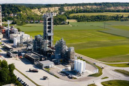 Industrieanlage mit mehreren Gebäuden und Silos, umgeben von grünen Feldern.