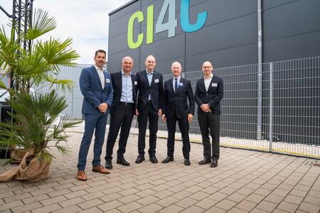 Fünf Männer in Businesskleidung stehen vor einem Gebäude mit der Aufschrift CI4C.