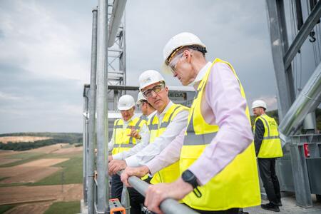 Mitarbeiter in Bauhelmen und Sicherheitswesten auf einer Baustelle.