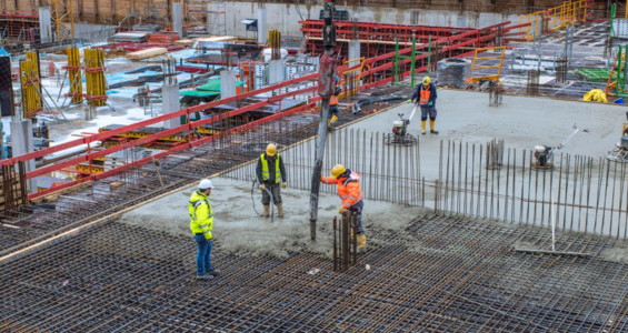 Bauarbeiter auf einer Baustelle beim Betonieren einer Fundamentfläche.