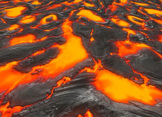 Glühende, orange-rote, flüssige Lava, durchzogen von schwarzem, abgekühltem Gestein als Leitmotiv für den Spezialbaustoff ThermoCem.