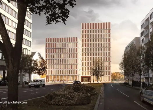 Zwei moderne, rechteckige Bürogebäude mit einer Fassade aus vertikal gegliederten Elementen stehen nebeneinander in einer städtischen Straße. Links und rechts der Straße befinden sich weitere Gebäude und parkende Fahrzeuge. Im Vordergrund liegt eine bepflanzte Verkehrsinsel, im Hintergrund ist ein heller Himmel mit warmem Abendlicht zu sehen.   Die Visualisierung zeigt die beide Baukörper des neues Polizeipräsidiums Rheinpfalz in Ludwigshafen. Die Ansicht entlang der Straße verdeutlicht die Höhenstaffelung 